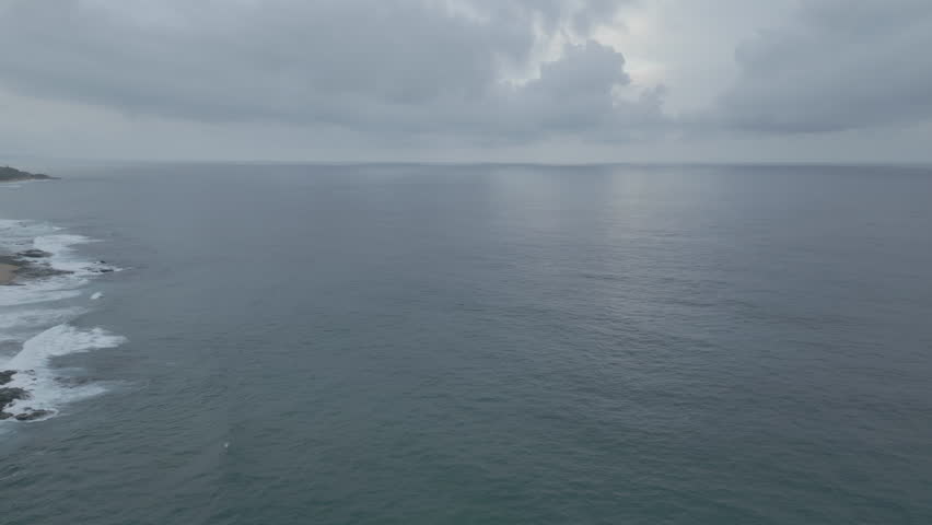 high flying over Indian Ocean on cloudy day during sunset showing ocean and revealing shore