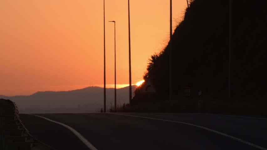 Cars circulating with the sun downing at sunset