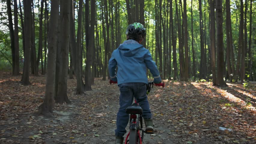 Boy riding on bicycle in the forest. 4k video footage UHD 3840x2160