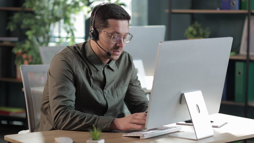Millennial man in glasses wearing headphones holding video call with clients partners. consulting online on helpline. talk with clients provide information strategizing remotely | Shutterstock HD Video #1101998697