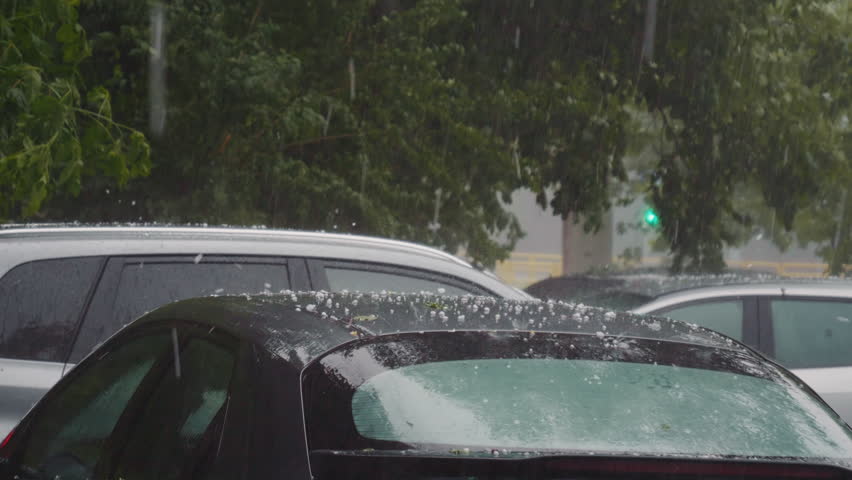 Hail during heavy rain falls on roof and windshield of black car. Impact caused by heavy storm and hail. | Shutterstock HD Video #1102001259