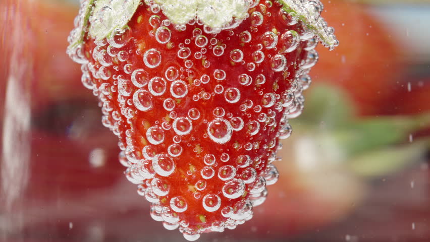 Strawberries under water in bubbles. Macro panorama.