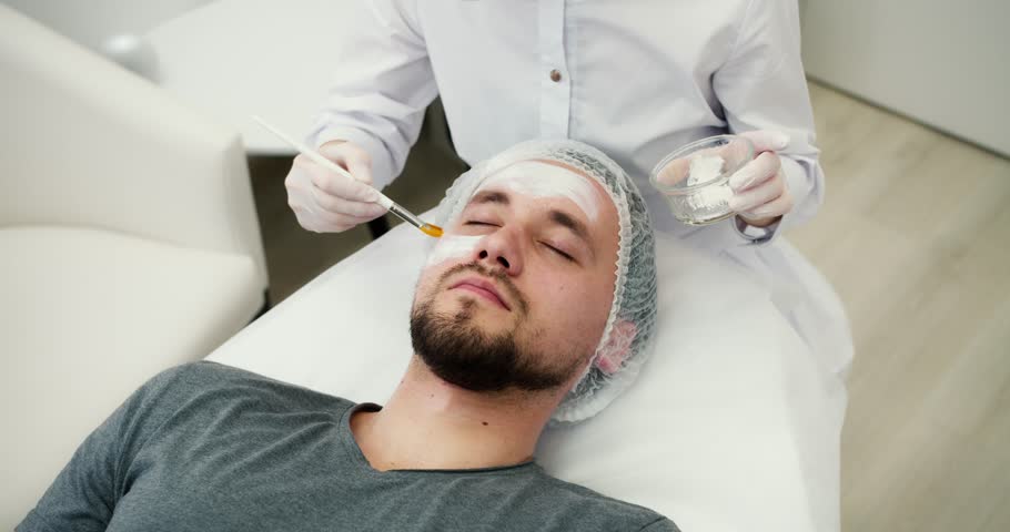 Unrecognizable beautician apply mask for face on man skin | Shutterstock HD Video #1102003585