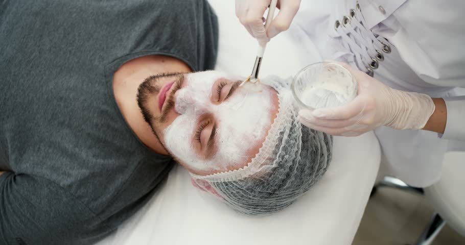 Close up of unrecognizable beautician apply mask for face on man skin | Shutterstock HD Video #1102003609