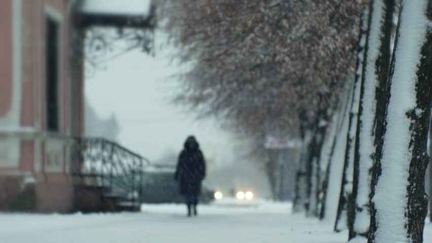 People pedestrians in a snowfall blizzard on a city street in cold winter Christmas weather