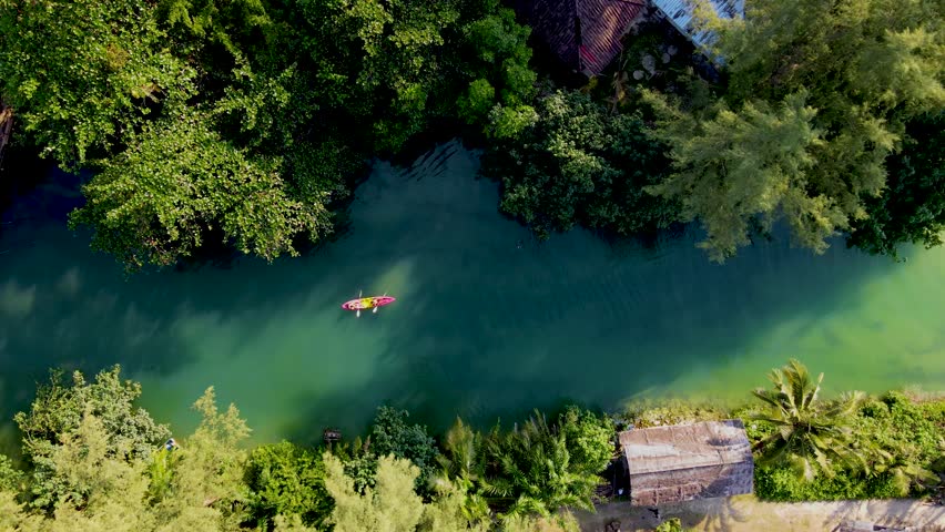 A couple of men and women in a kayak on the tropical island Koh Chang Thailand, drone view at the kayak in a tropical river in the jungle forest of Koh Chang during sunset