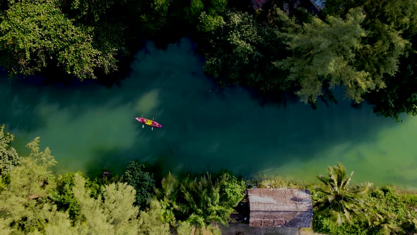 A couple of men and women in a kayak on the tropical island Koh Chang Thailand, drone view at the kayak in a tropical river in the jungle forest of Koh Chang during sunset