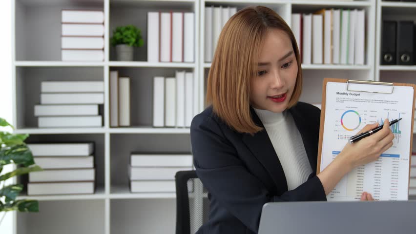 Young Asian business woman employee or executive manager using computer looking at laptop and talking leading hybrid conference remote video call virtual meeting or online training working in office. | Shutterstock HD Video #1102008775
