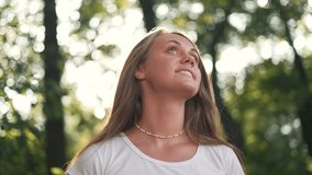 Face of beautiful white girl looking away into park in sun. open face of smiling white girl. Happy cheerful girl in park with long hair with positive emotions. sunny day