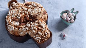 Colomba pasquale-Italian Easter cake on the kitchen table. Easter cake in the shape of a dove with almonds and orange peel. Traditional Italian pastries. paschal eggs in a bowl in the form of a rabbit - Powered by Shutterstock - Get 15% off with code: PIKWIZARD15
