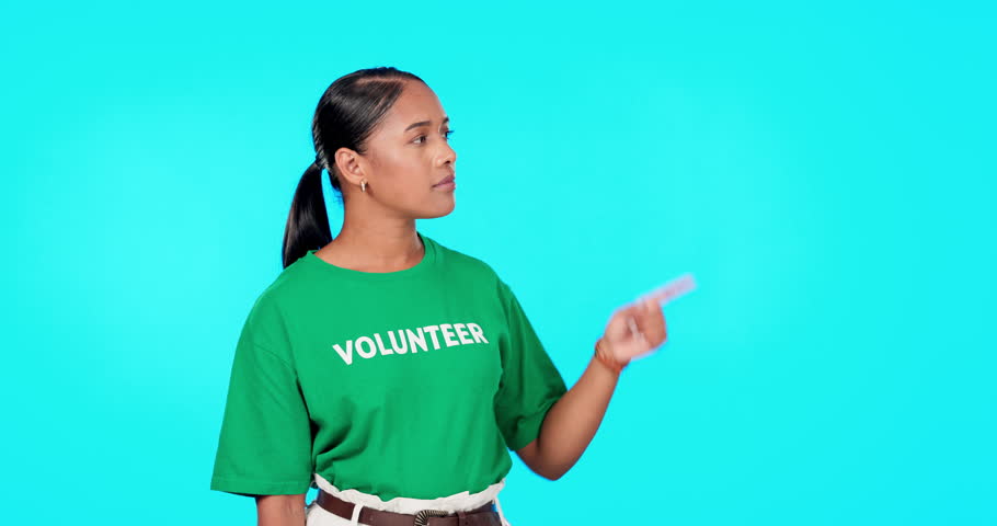 Volunteer woman pointing to empty space isolated on blue background text, product placement or advertising. Ngo, nonprofit and charity worker or biracial person face in studio, promo or presentation | Shutterstock HD Video #1102018981