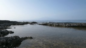 Waves breaking on the rocks. Etna volcano in the background. Sicily. Italy. Super slow motion 4K