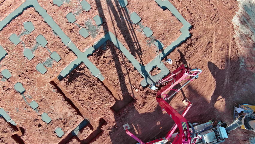 As workers pour concrete for foundation of building using an automatic pump is being directed
