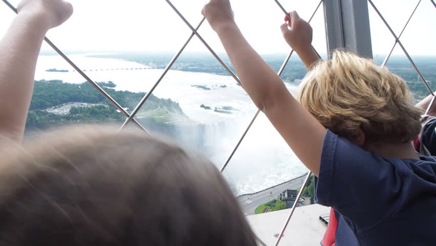 Children looking at Niagara Falls from observation tower on summer vacation 