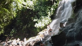 People bathe in a waterfall, people bathe in a mountain waterfall. Big beautiful waterfall