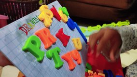 Close up shot of A child's hand plays with plastic letters
