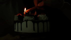 Cake happy birth day concept, slow motion kid blowing fire candle on cake of happy birth day cake on dark night background, close up view video cake on hand of party in dark night screen background