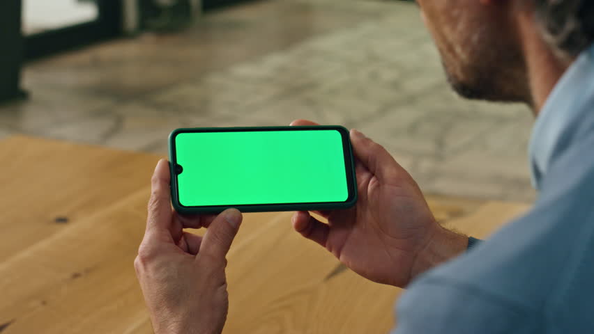 Closeup businessman watching mockup phone indoors. Unknown formal boss using chroma screen smartphone. Adult director hands holding horizontal green display cellphone online. Communication concept  Royalty-Free Stock Footage #1102032323