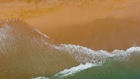 Beautiful beach and sea. Waves roll on the sandy shore. Waves on the sand, a soothing picture of a vacation, an aerial view of the beach. Meeting place of the ocean and land. Slow motion 120fps video