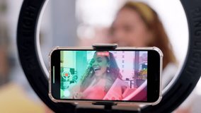 Woman, makeup influencer and smartphone with ring light for live streaming, eyeshadow palette or screen on social media. Girl talking, beauty expert and face for cosmetics with excited wave at phone - Powered by Shutterstock - Get 15% off with code: PIKWIZARD15