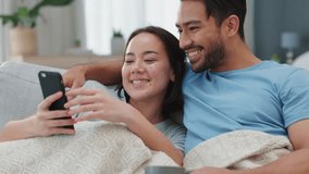 Relax, sofa and couple with a smartphone talking of social media, funny video online or meme. Young gen z woman and man or people with cellphone watching comedy content on mobile digital app together
