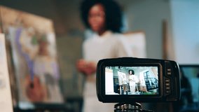 Camera is filming an art class of an african-american woman