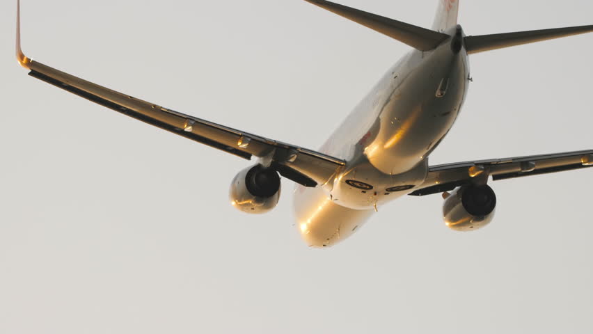 Unrecognizable jet aircraft flies, backlight sunset, leaving. Rear view, passenger airliner climb after takeoff