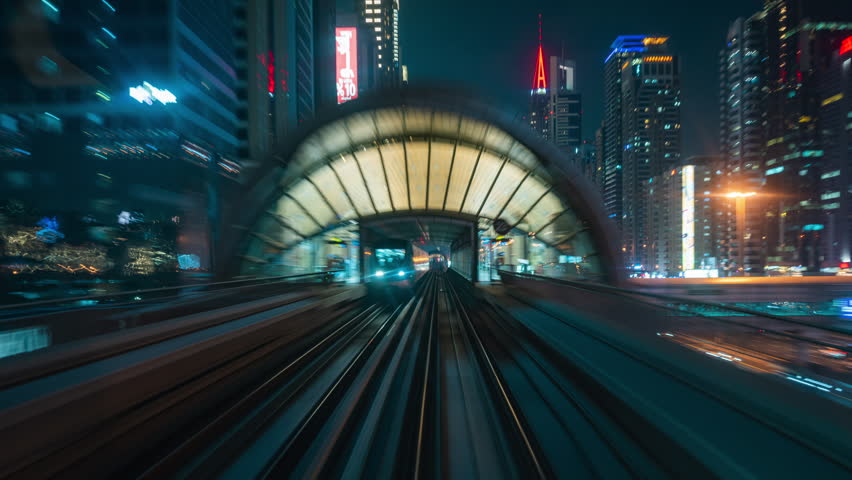 Motion timelapse view of journey on the modern driverless Dubai elevated Rail Metro System running alongside the Sheikh Zayed Road at night in Dubai, United Arab Emirates (UAE).  Royalty-Free Stock Footage #1102037615