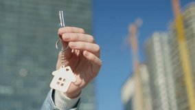 Hand with keychain in shape of small house and keys. Against backdrop of typical American country-style house. Construction, sale or purchase of apartments. Developer, realtor or real estate agency. - Powered by Shutterstock - Get 15% off with code: PIKWIZARD15