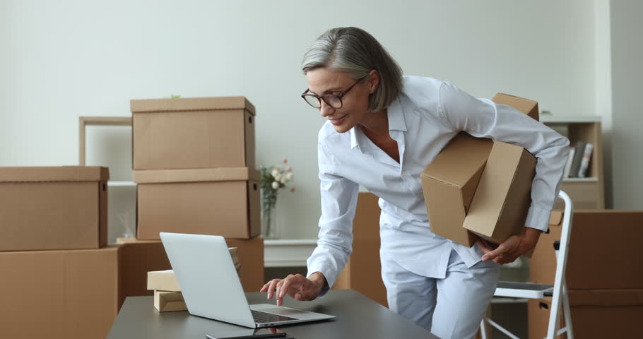 Female individual entrepreneur, small business owner manage orders, prepare parcels for sending to customer working from warehouse use laptop. E-commerce, shipment, transporting services, dropshipping Royalty-Free Stock Footage #1102040365