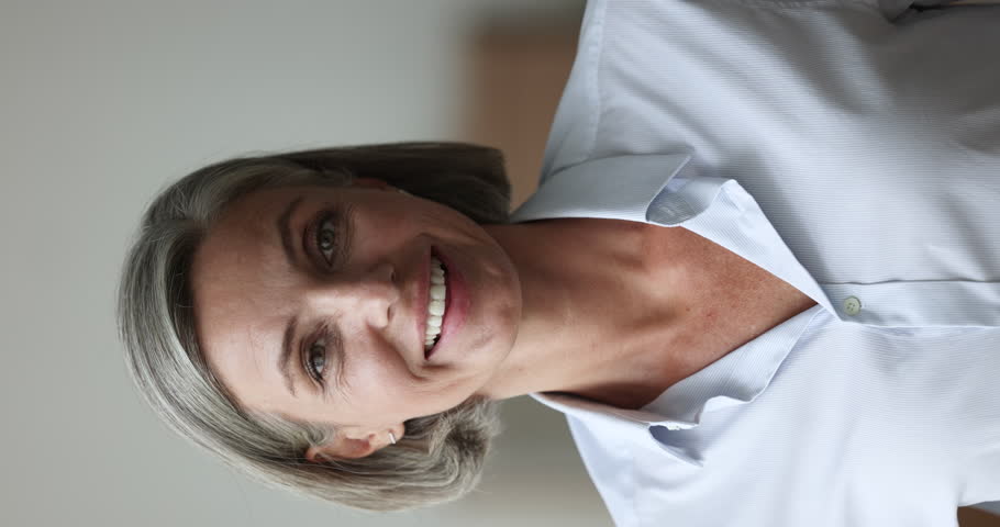 Happy mature woman stand indoor pose look at camera, laughs, revealing perfect white straight teeth, advertise dental clinic, orthodontics professional services. Portrait of friendly teacher, close up | Shutterstock HD Video #1102040373