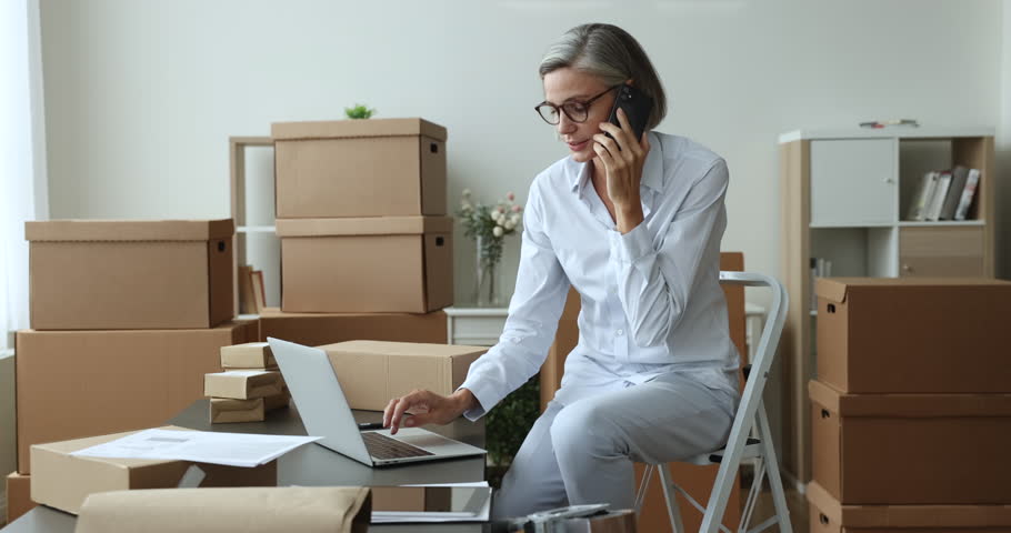 Mature businesswoman, small business owner provide best customer service to client by phone call, manage returns, refunds, answers queries about products, working from warehouse using laptop and cell Royalty-Free Stock Footage #1102040385