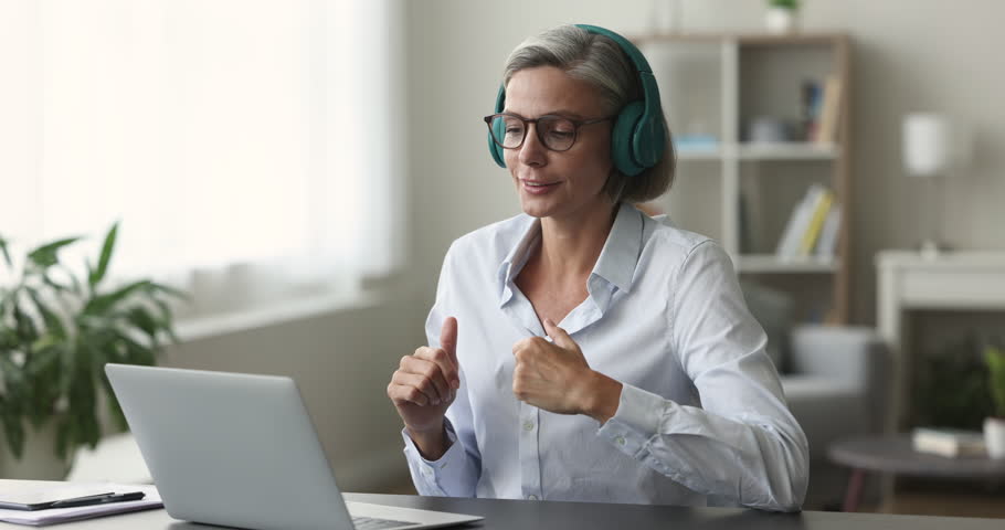 45s businesswoman or teacher in headphones talk to client or learner use video call app, sit at desk look at laptop make speech, provide help, explanations at formal virtual meeting. Tuition, business Royalty-Free Stock Footage #1102040415
