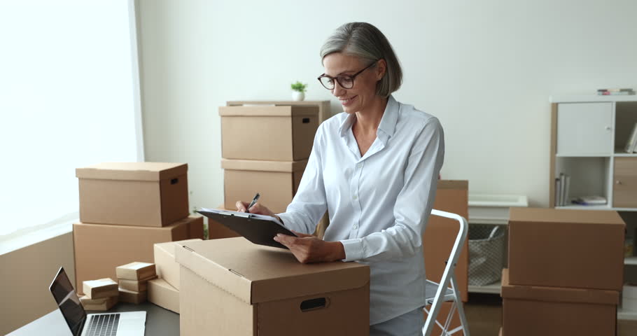 Attractive businesswoman, small business, online store owner manage inventory, check customers list, prepare parcels for sending to clients working from warehouse room. Dropshipping, retail, business Royalty-Free Stock Footage #1102040429