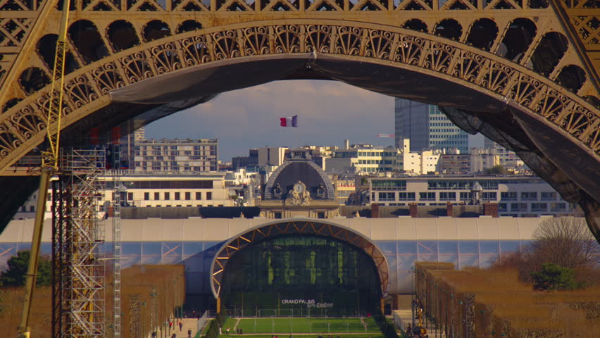 Close-up view through the Eiffel Tower on the french flag against the blue sky