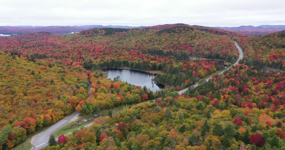 State Highway 3 slices through the colorful autumn landscape past Panther Pond near Panther Mountain Bog in Adirondack Park in Upstate New York.