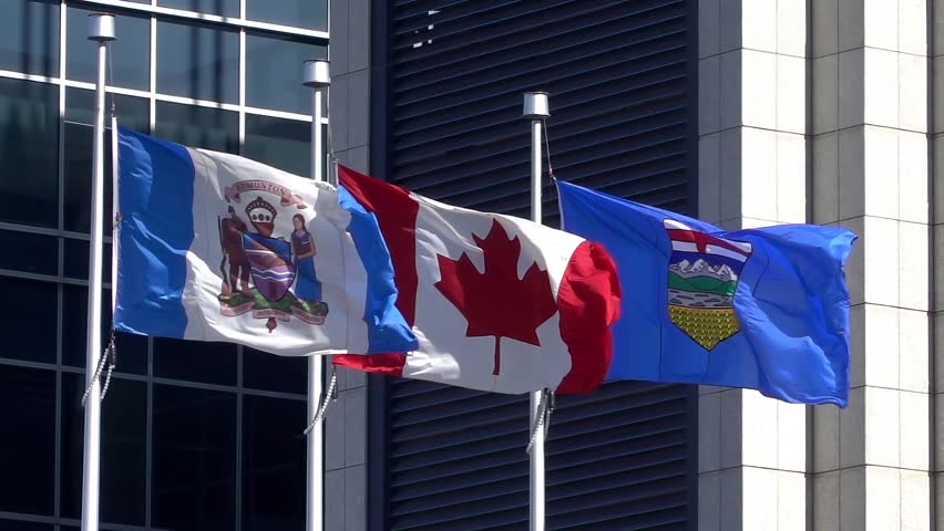 A flag of the City of Edmonton with a Canadian flag and an Alberta flag waving in slow-motion.