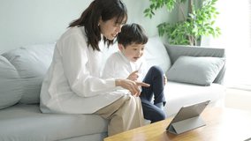 Parent and child sitting on the sofa and looking at the screen of the tablet PC