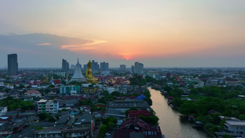 
aerial view golden big Buddha Wat Paknam Phasi Charoen in sunset. 
beautiful sunset reflection on a canal in front big buddha. 
scenery sky in twilight background.the one famous landmarks in Thailand