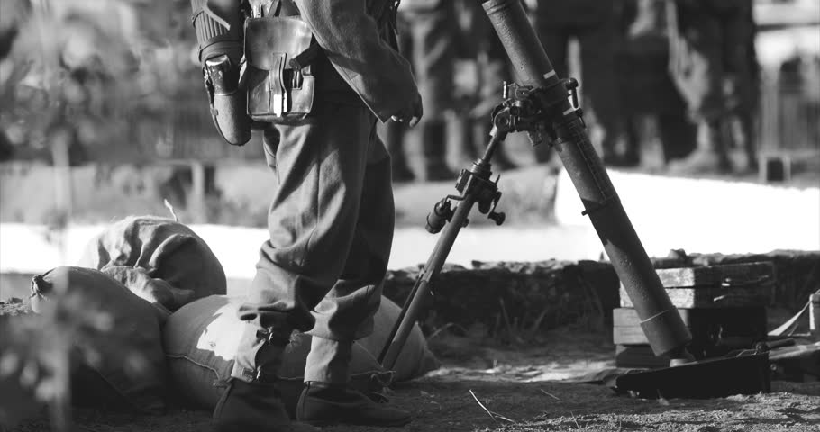 Close-up View On Re-enactor Dressed As German Wehrmacht Infantry Soldier In World War Ii With Submachine Gun Mp 40 Patrols Territory Of Mortar Crew. German Soldier Guards Mortar. Black And White Video