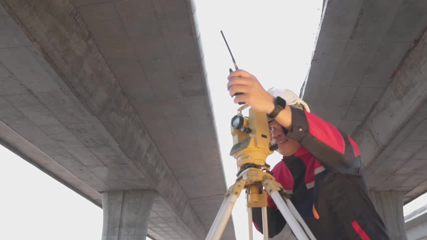 A surveyor engineers worker making measuring and pointing finger with theodolite on road works. Survey engineer at road construction site, Surveyor equipment. Highway. Royalty-Free Stock Footage #1102051851