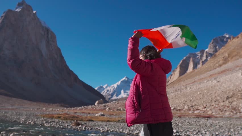 Young Indian woman walking in front of Gonbo Rangjon mountain and waving Indian flag at Zanskar, Ladakh, India. Patriotism, independence day August 15 and holidays concept.