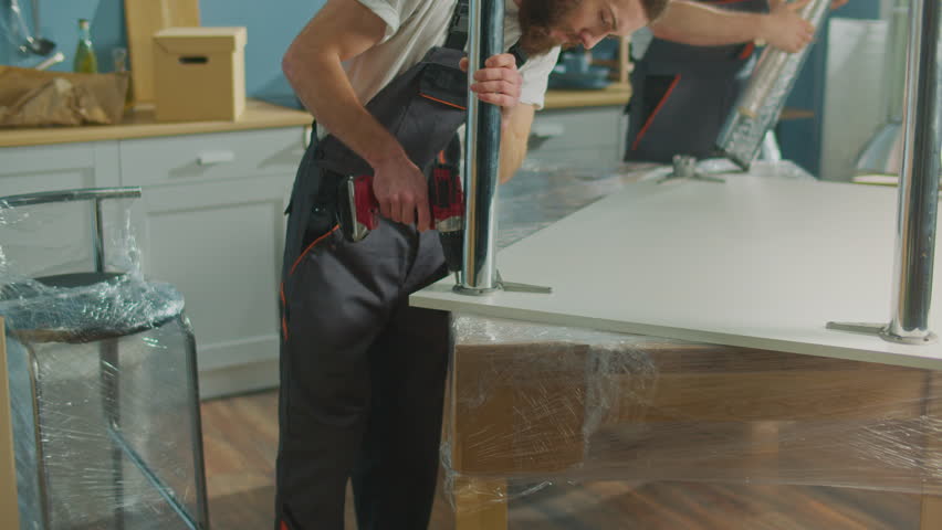 Workers of Moving Company With Uniforms Carefully Packing Furniture. Furniture and Equipment Disassembly and Assembly. Travel insurance. Team of Employee Workers Helps Customers to Relocation.