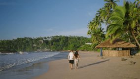 Young biracial happy couple unfocused walking on the beach together enjoying summer backview shot from distance. Smiling boyfriend and girlfriend relaxing and taking a walk at the seaside at sunrise. - Powered by Shutterstock - Get 15% off with code: PIKWIZARD15