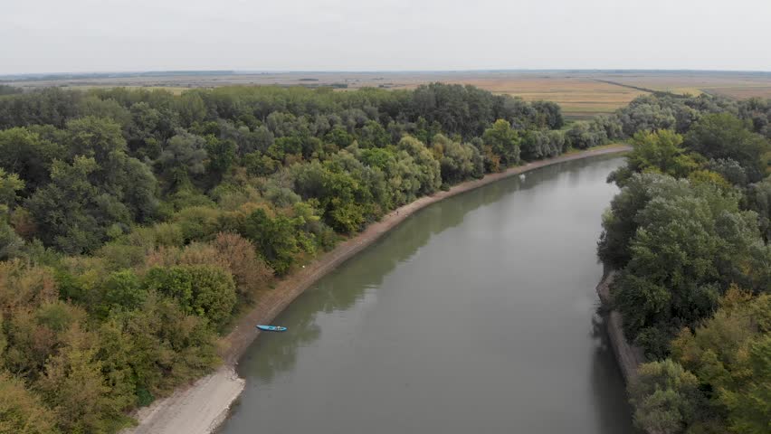 Bend of the plain river with banks overgrown with different trees. Beautiful colors of nature on spring season. Aerial view.
Aerial view of the wide river with two green shores 4K.