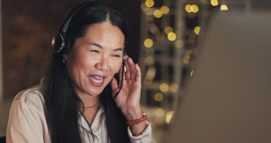 Call center, consulting or Asian woman explaining in office, customer services or communications company. Contact us or sales agent in microphone headset at crm or technical support at night Royalty-Free Stock Footage #1102058575