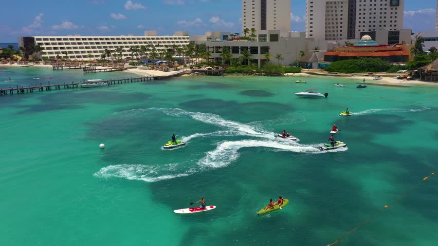 Aerial view of riding people on jet ski (personal watercraft) and Stand up paddle (SUP). Caribbean beach on Cancun hotel zone, Mexico. Royalty-Free Stock Footage #1102061145