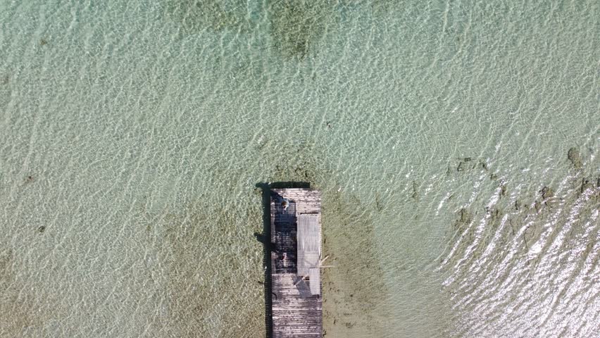 Aerial top shot of waterfront in clear sea in Lake Vouliagmeni, Loutraki Greece | 4K