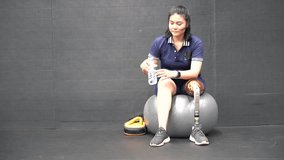 Disabled woman wearing prosthetic leg Exercise Lei Yoga Tired Thirsty Drink water holding a bottle of water - Powered by Shutterstock - Get 15% off with code: PIKWIZARD15
