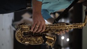 caucasian male musician in a blue shirt with a wedding ring on his hand plays the saxophone, vertical video. Close up footage of Musician saxophonist plays music on his instrument. vertical video - Powered by Shutterstock - Get 15% off with code: PIKWIZARD15